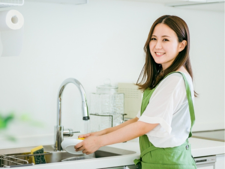 システムキッチンでお皿を洗っている女性